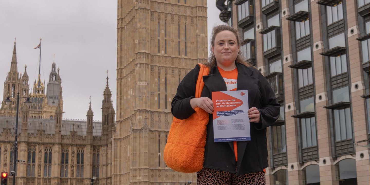 Phoebe Day stood in front of Big Ben, holding the MS Society Manifesto