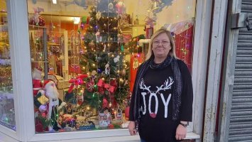 Ann-Marie stands in front of a festively decorated MS Society shop