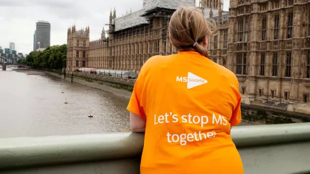 Photo shows a woman on a bridge outside the Houses of Paliament wearing a t-shirt that says Let's stop MS together