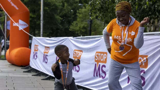  A person and a child dance, with Stop MS signs in the background