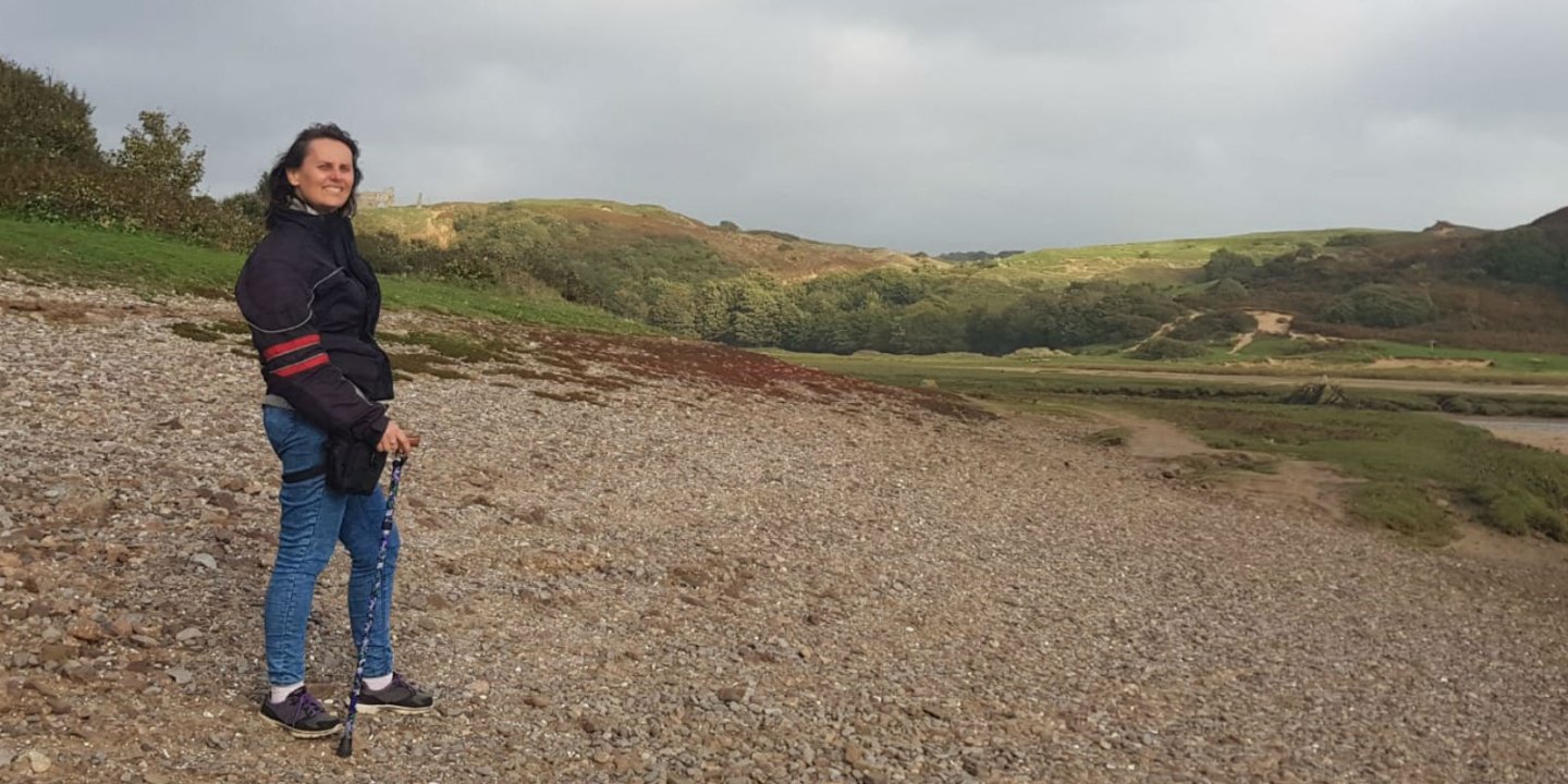 Florence stands on a beach, using a stick. 