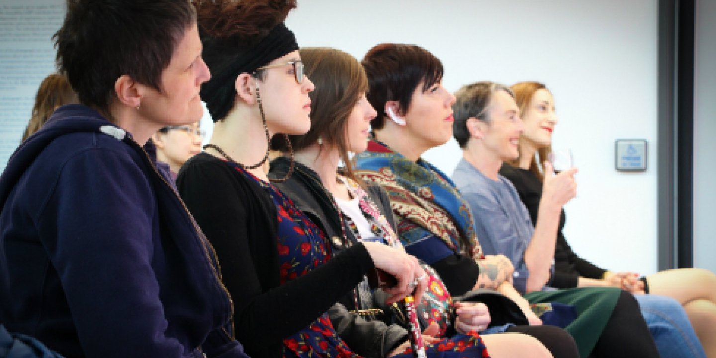 Photo: a group of people sitting in a row of chairs listening to a talk