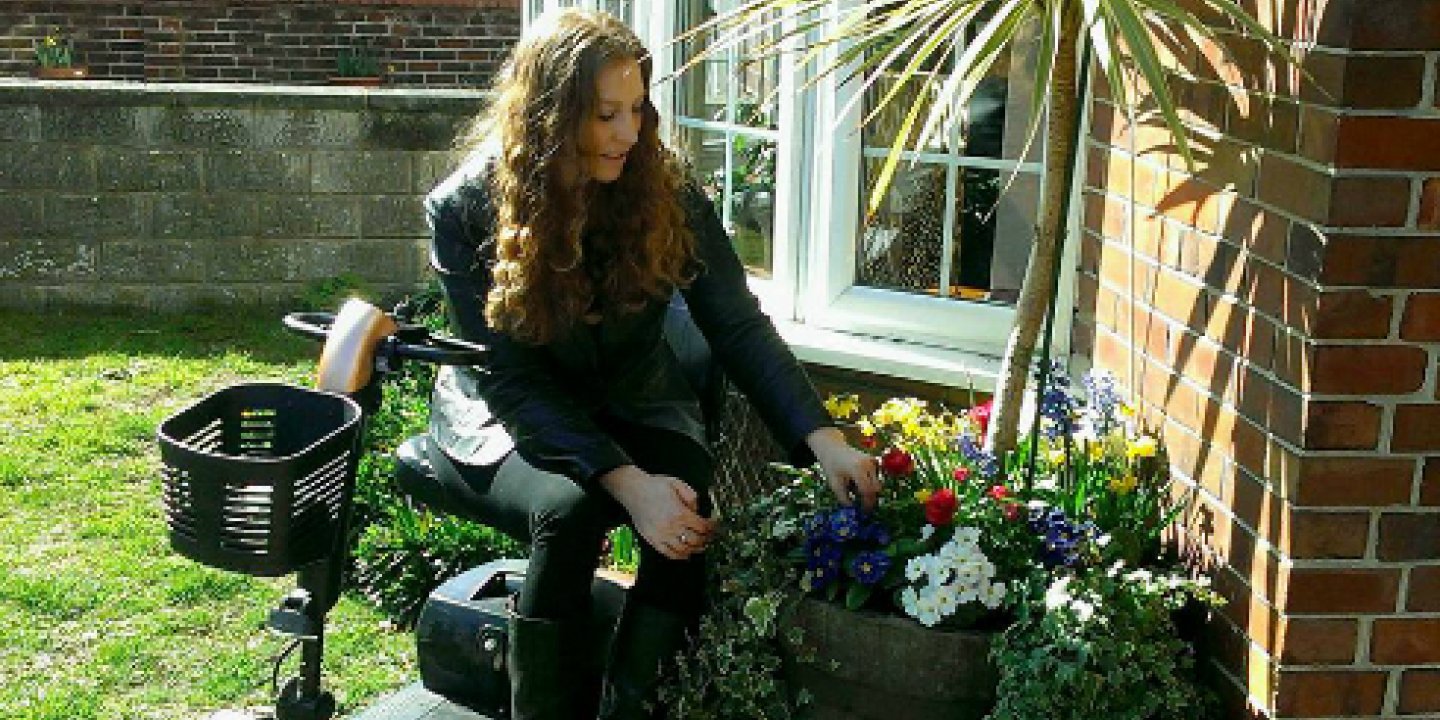 Shana in front of her flat, surrounded by plants and flowers