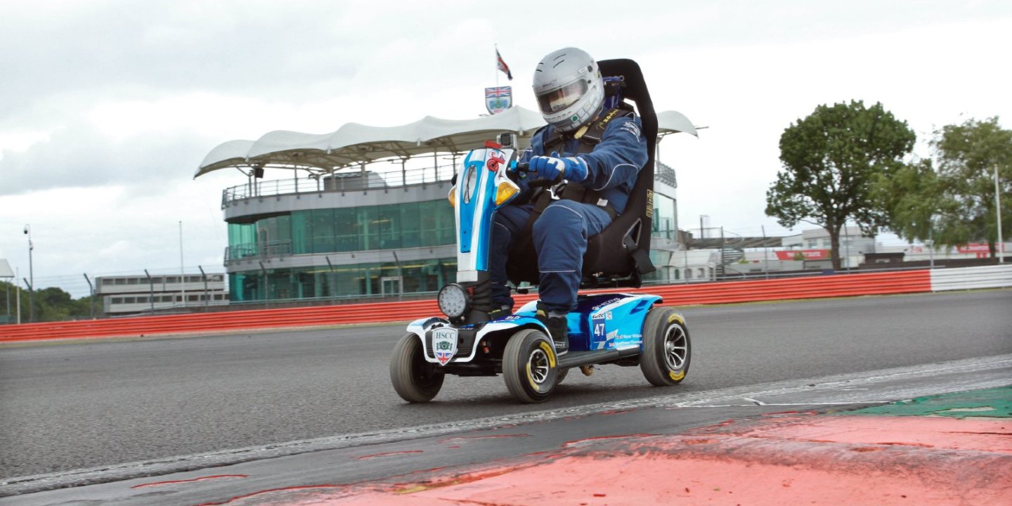 Noel racing his scooter with trees in the background