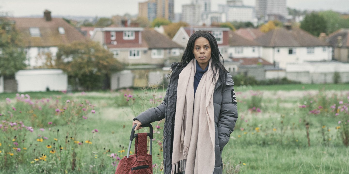 Brieann stands with a suitcase with a cityscape behind her.