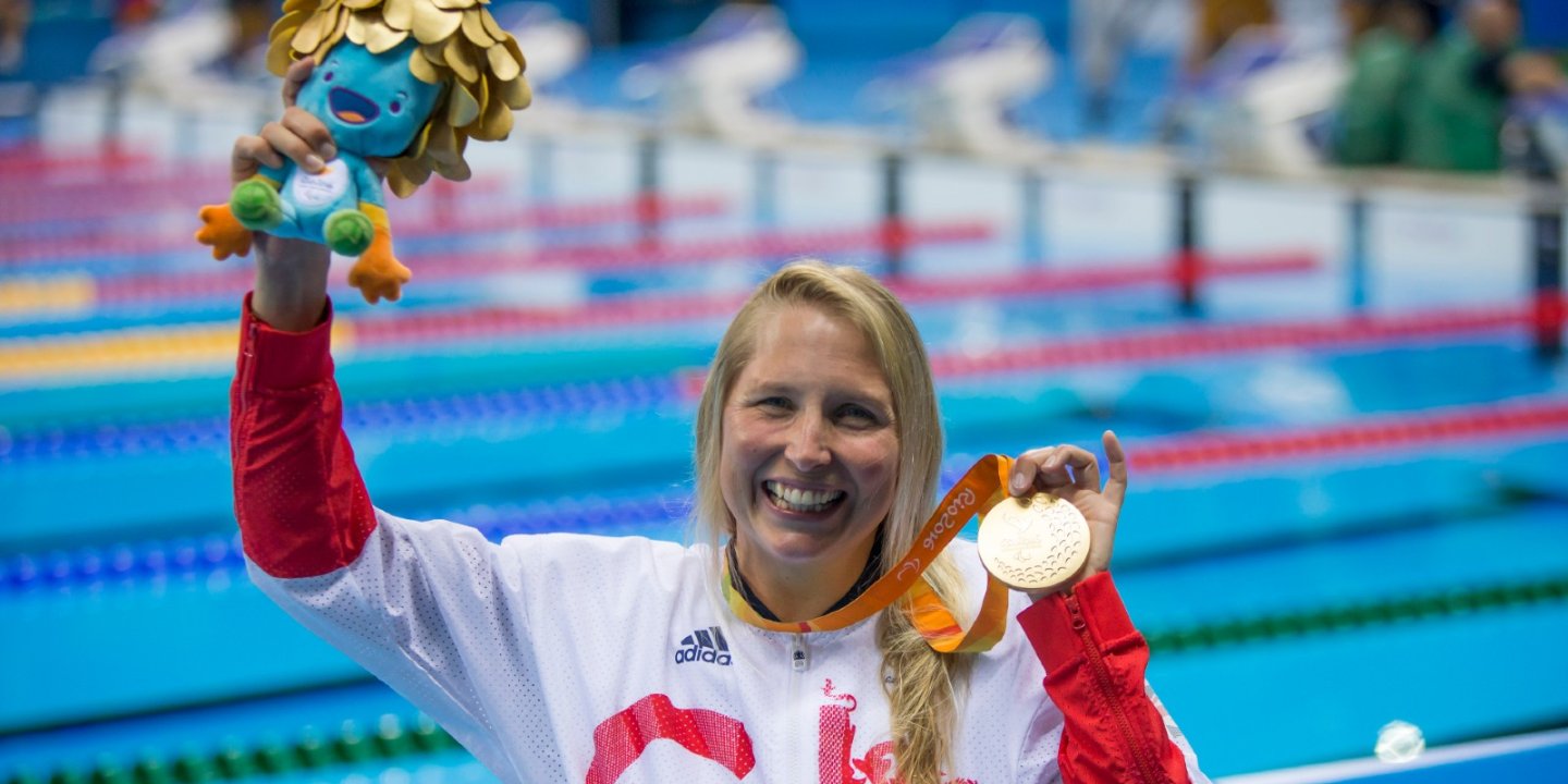Stephanie picture by pool in Rio at Paralympics holding up gold medal and smiling