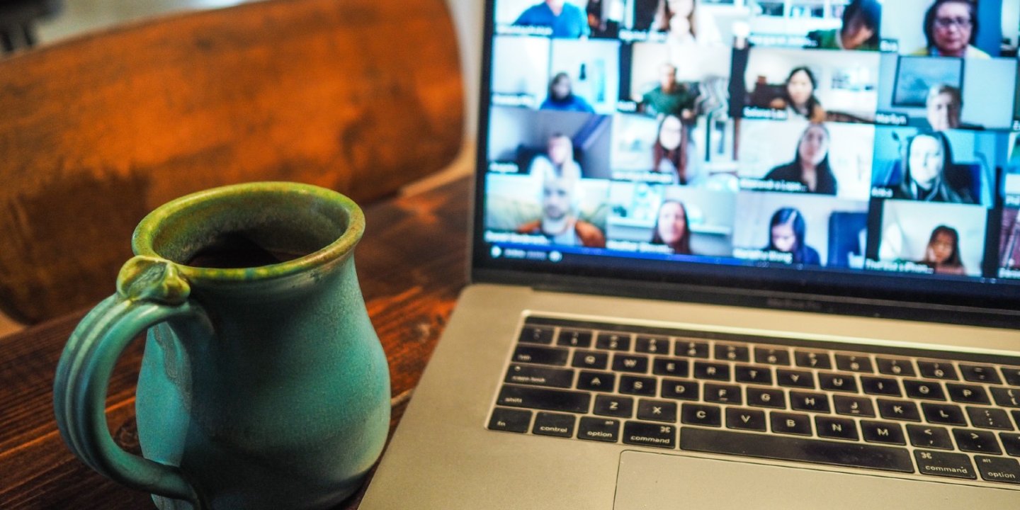 Mug next to a laptop showing a screen full of people on a video chat
