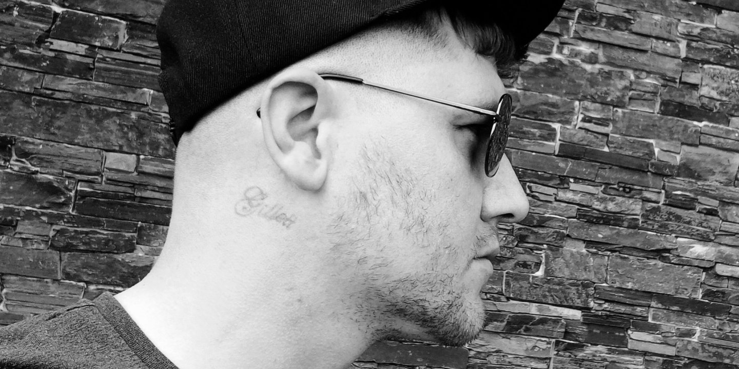 A black and white profile shot of Robbie wearing a baseball cap and sunglasses and