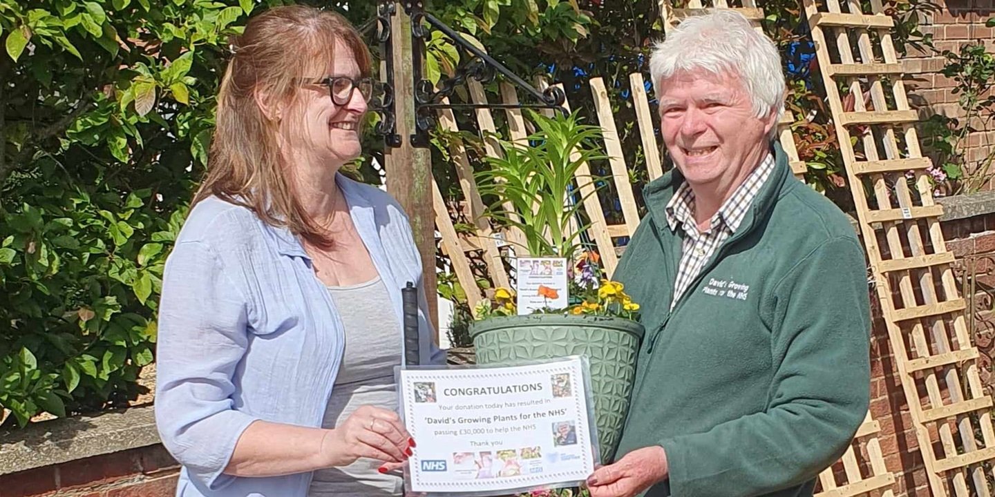 A man handing a woman a lily pot and certificate