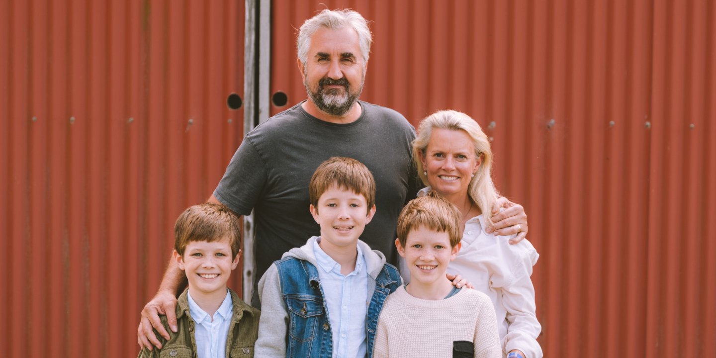 Picture of a man and woman standing with three boys