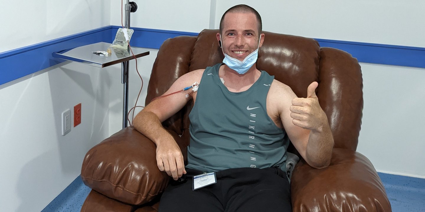 A man in a chair receiving treatment giving a thumbs up