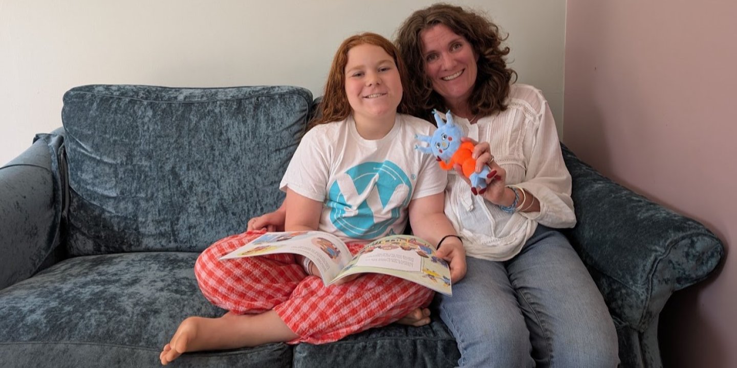 Ailsa and her daughter sitting on a sofa with Tingo soft toy and children's book