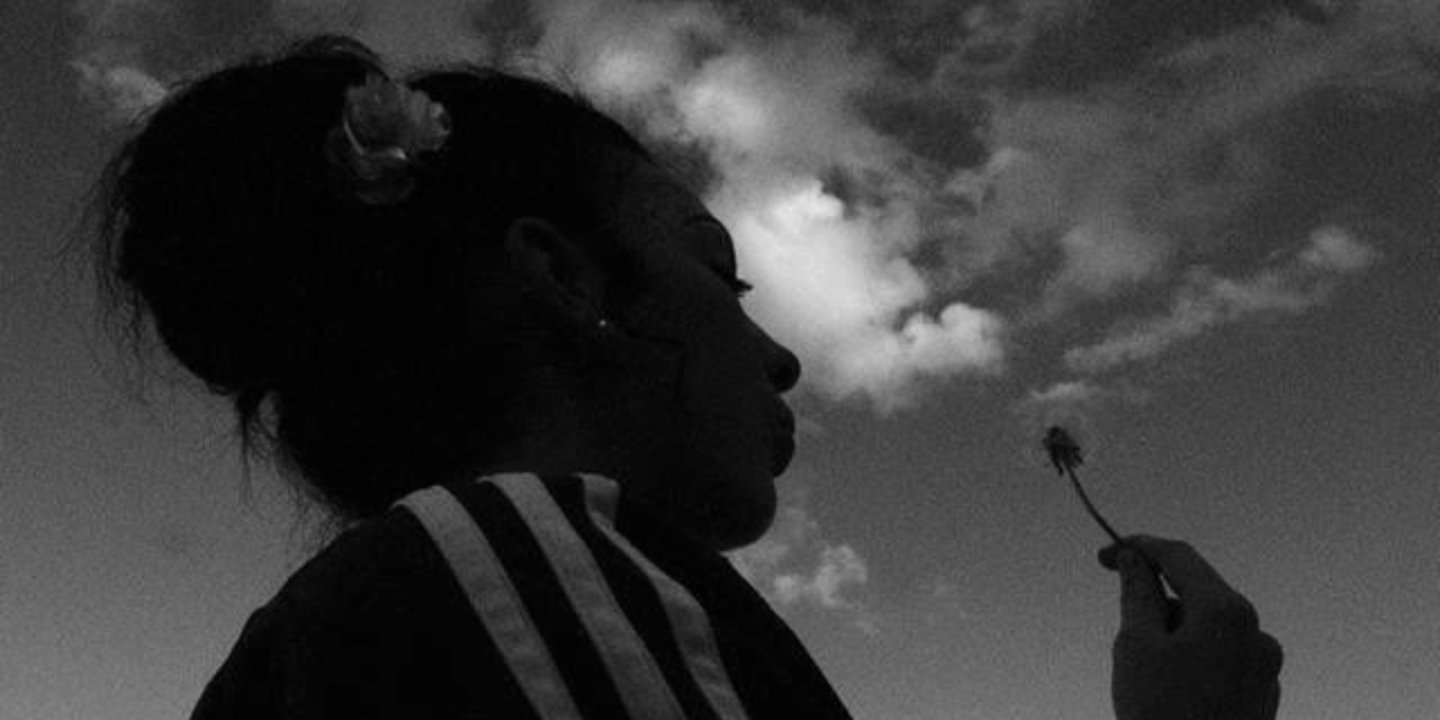 A black and white photograph of a girl with a dandelion.