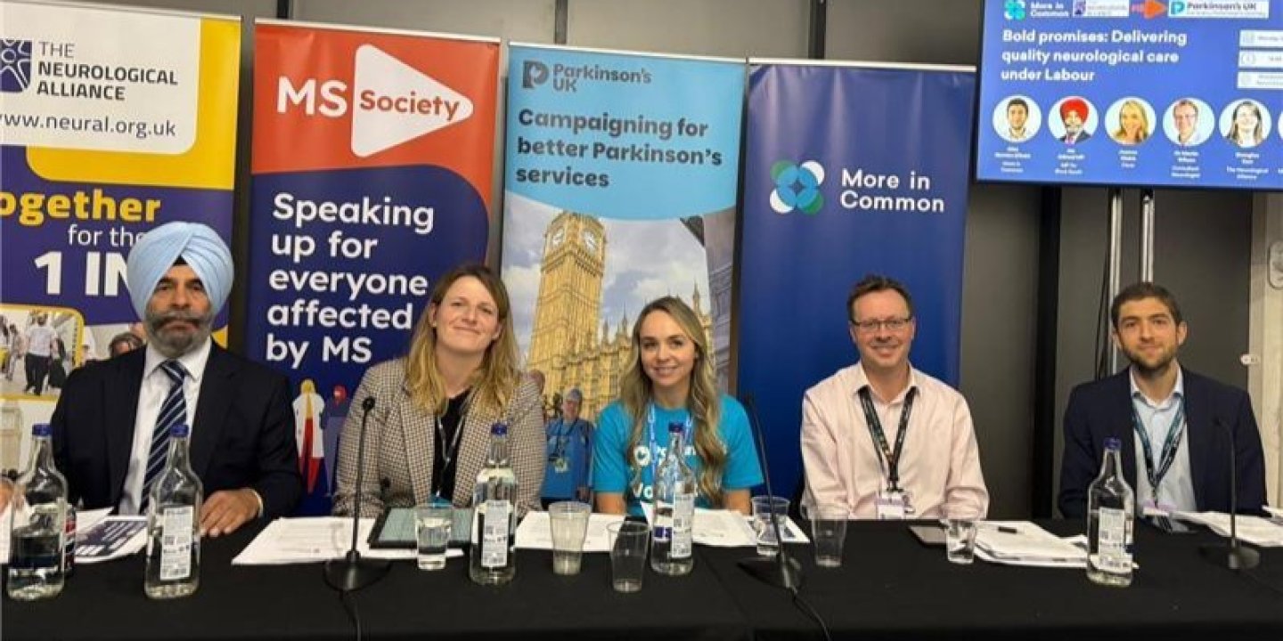 A group of people sat at a table in front of organisations' signs