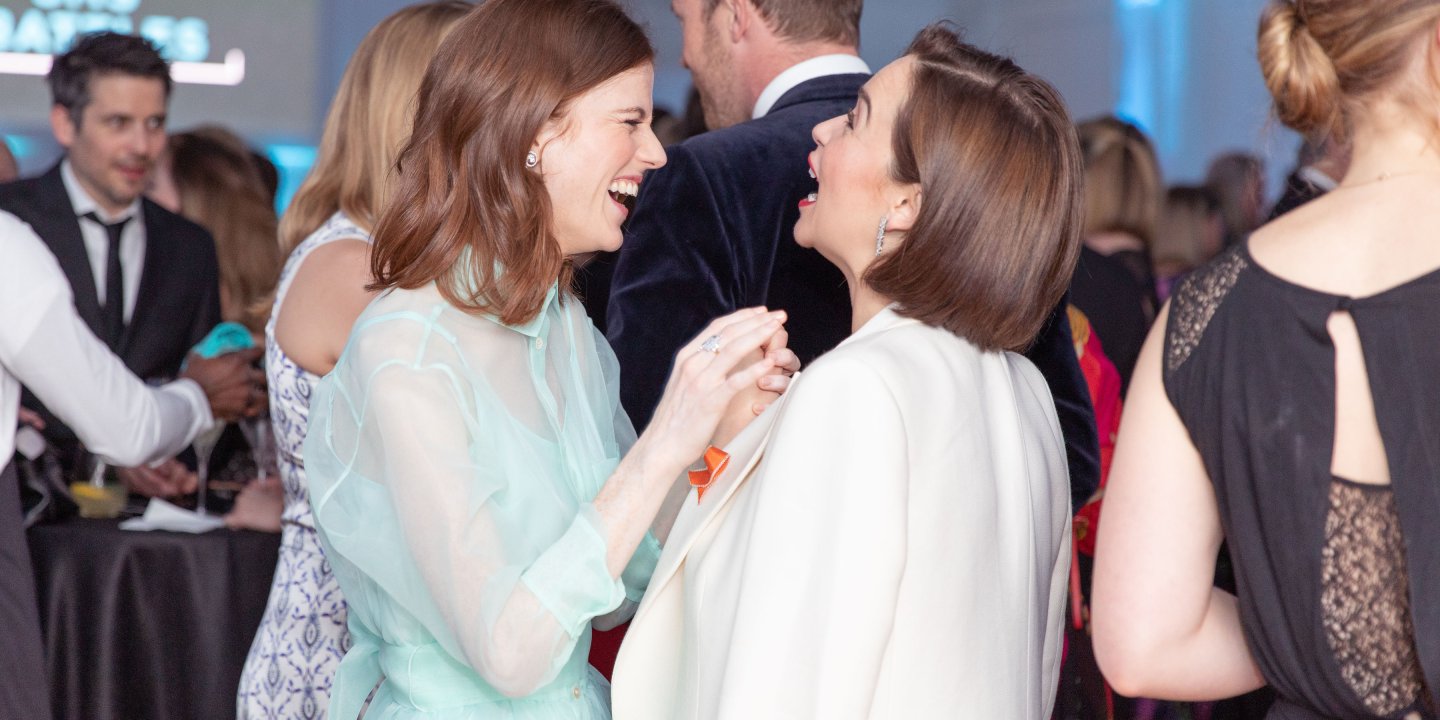 Two women laughing together at a formal event