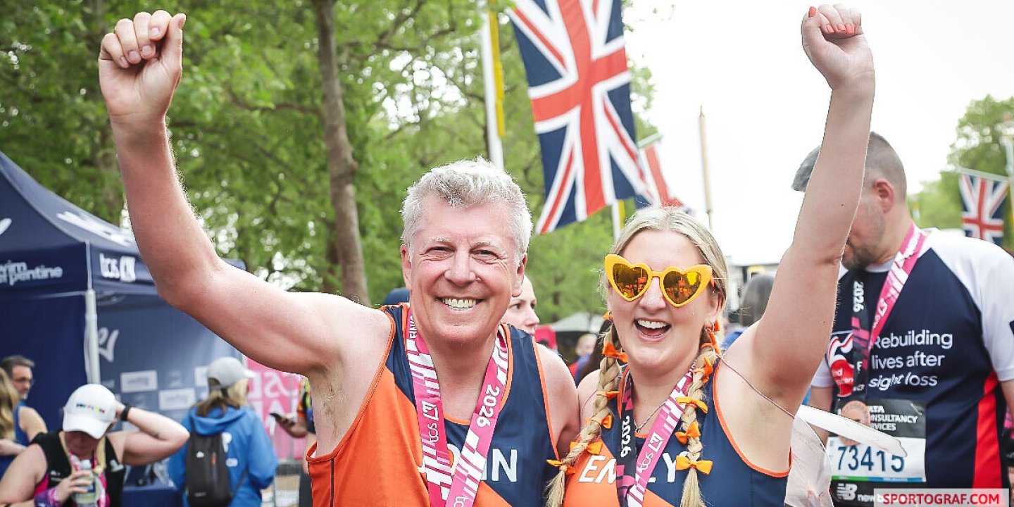 Emily and her dad fist-pump the air and wear MSS running vests at the London Marathon