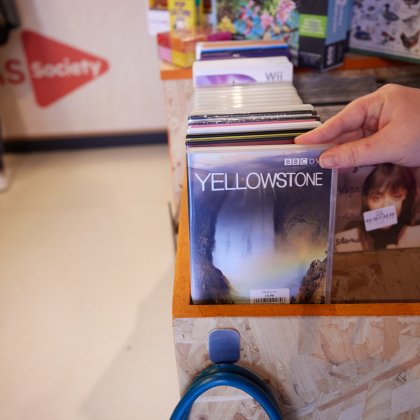 A display of DVDs and CDs with a hand reaching to pick out one