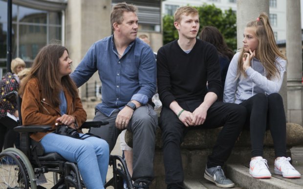 A group of people sit beside some steps, chatting.