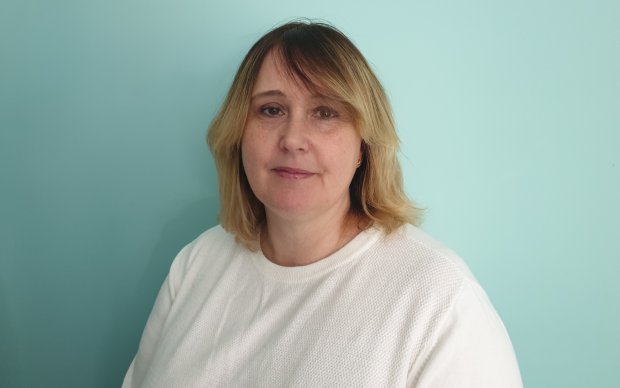 The photo shows Sam Walker smiling at the camera against a pale blue background.