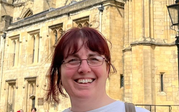 The photo shows Natalie smiling at the camera with a cathedral in the background.