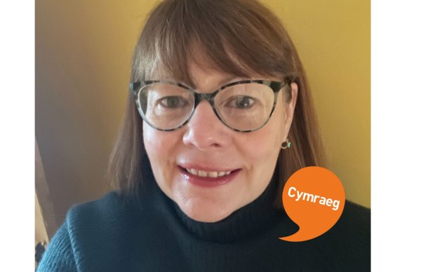 Image shows a woman with brown hair smiling. Cymraeg logo