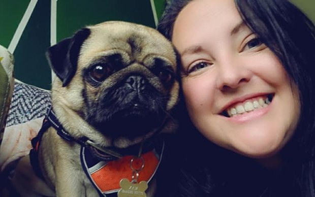 Jemma is smiling at the camera with her pug next to her.