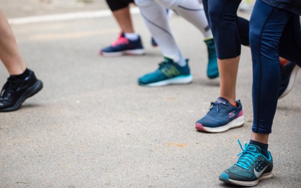 Image of people's legs and feet during a run on a concrete road