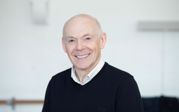 Headshot of Chris Murray, wearing a black jumper over a white shirt, against a white background