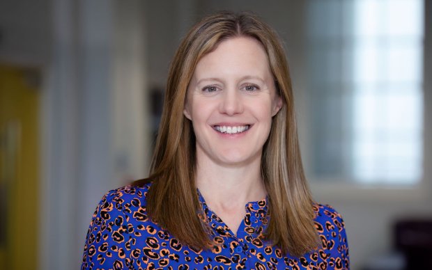 Headshot of Polly, who has long blond brown hair and wears a royal blue patterned blouse