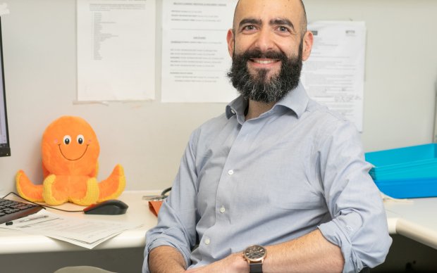A doctor sits at a desk with an orange toy octopus on it