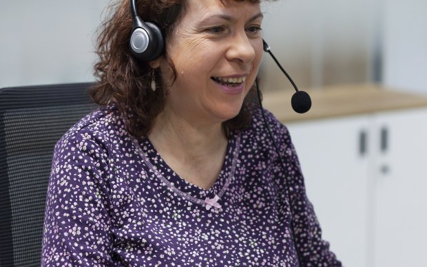 A person in a headset smiles as they talk to someone on the phone