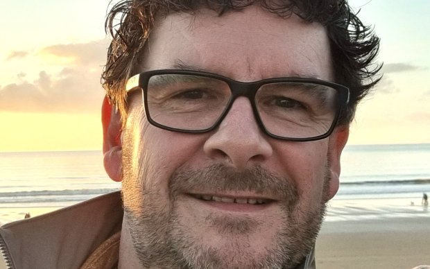 A headshot of a man in glasses