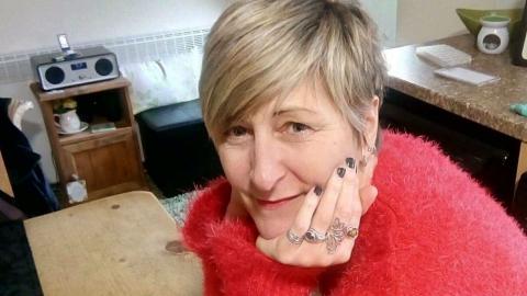 Caz. She has short blond hair and is wearing a red jumper.
