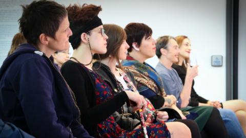 Photo: a group of people sitting in a row of chairs listening to a talk