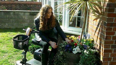 Shana in front of her flat, surrounded by plants and flowers