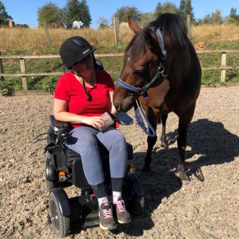 Emma outside in wheelchair next to her horse