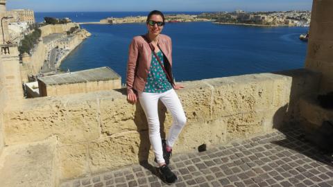 Sarah on holiday on an old wall with the sea in the background