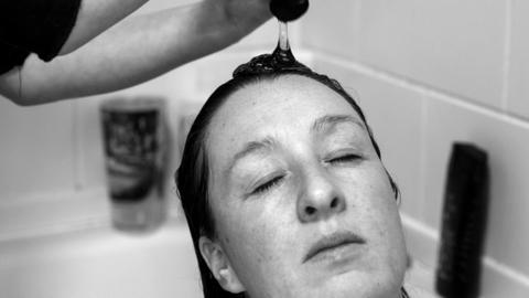 Black and white image of Kirsty having her hair washed