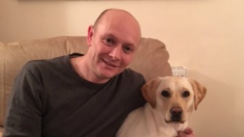 Image shows blogger Chris sat on a sofa with his dog