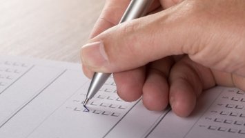 Photo: a hand writing on some forms
