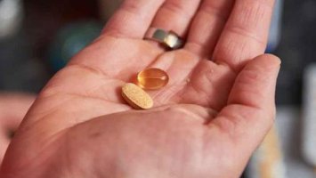a photo of a hand holding some orange pills