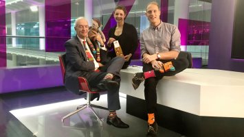 James and  Lianne with Jon Snow who is wearing a pair of their colourful socks.