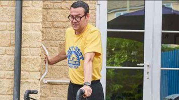 A photo of a man in a yellow t shirt walking with walking aid