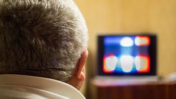 Image shows a man watching tv