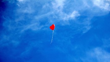 Heart shaped balloon floating in blue sky