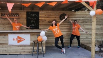 Three fundraisers wearing MS Walk t-shirts with hands outstretched