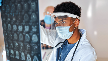 Researcher wearing a mask looks at MRI scans