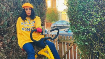 Roxanne sits on a bike. She's wearing a yellow beret and yellow sweatshirt. 