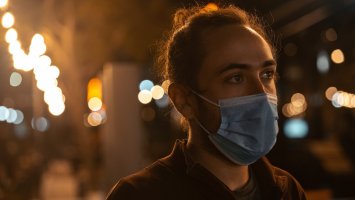 A man wearing a face mask out in the city in the evening