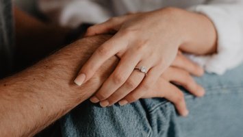 two people holding hands sat on a bed